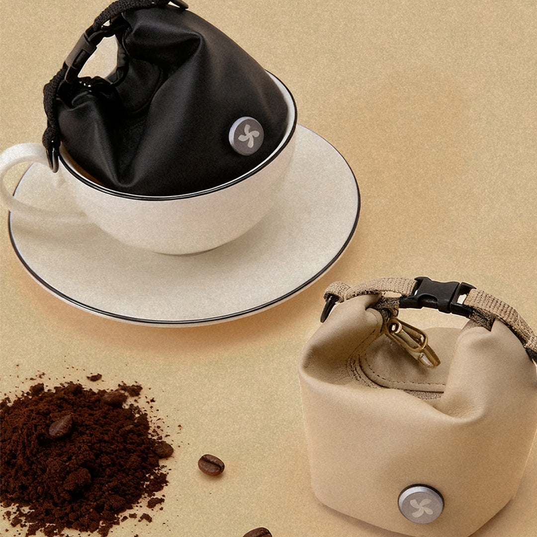Black and beige mini bags made from recycled coffee grounds fabric, styled with coffee beans and grounds.