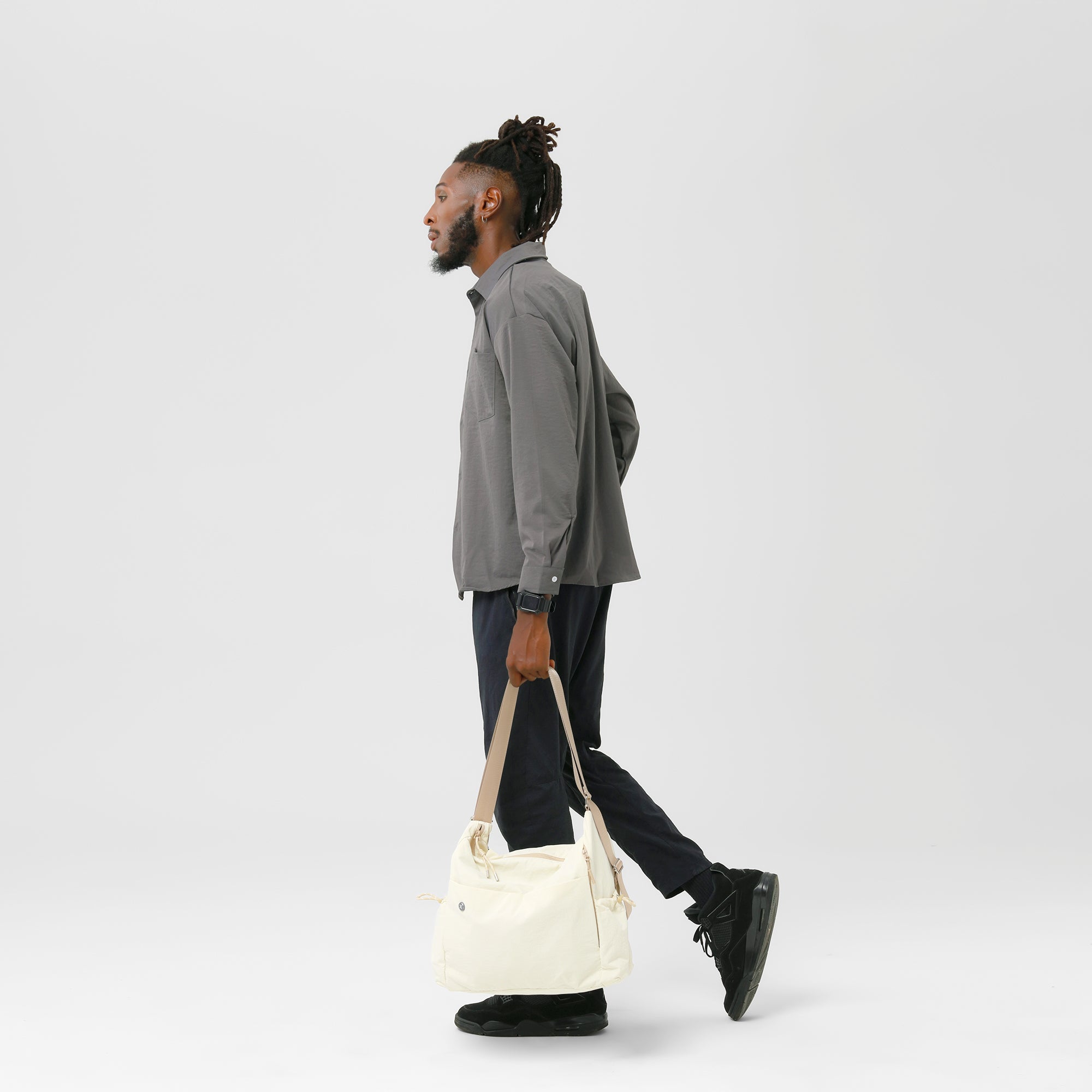 Man walking with Air Convert Tote, showcasing organic fabric and stylish versatility for urban lifestyles.