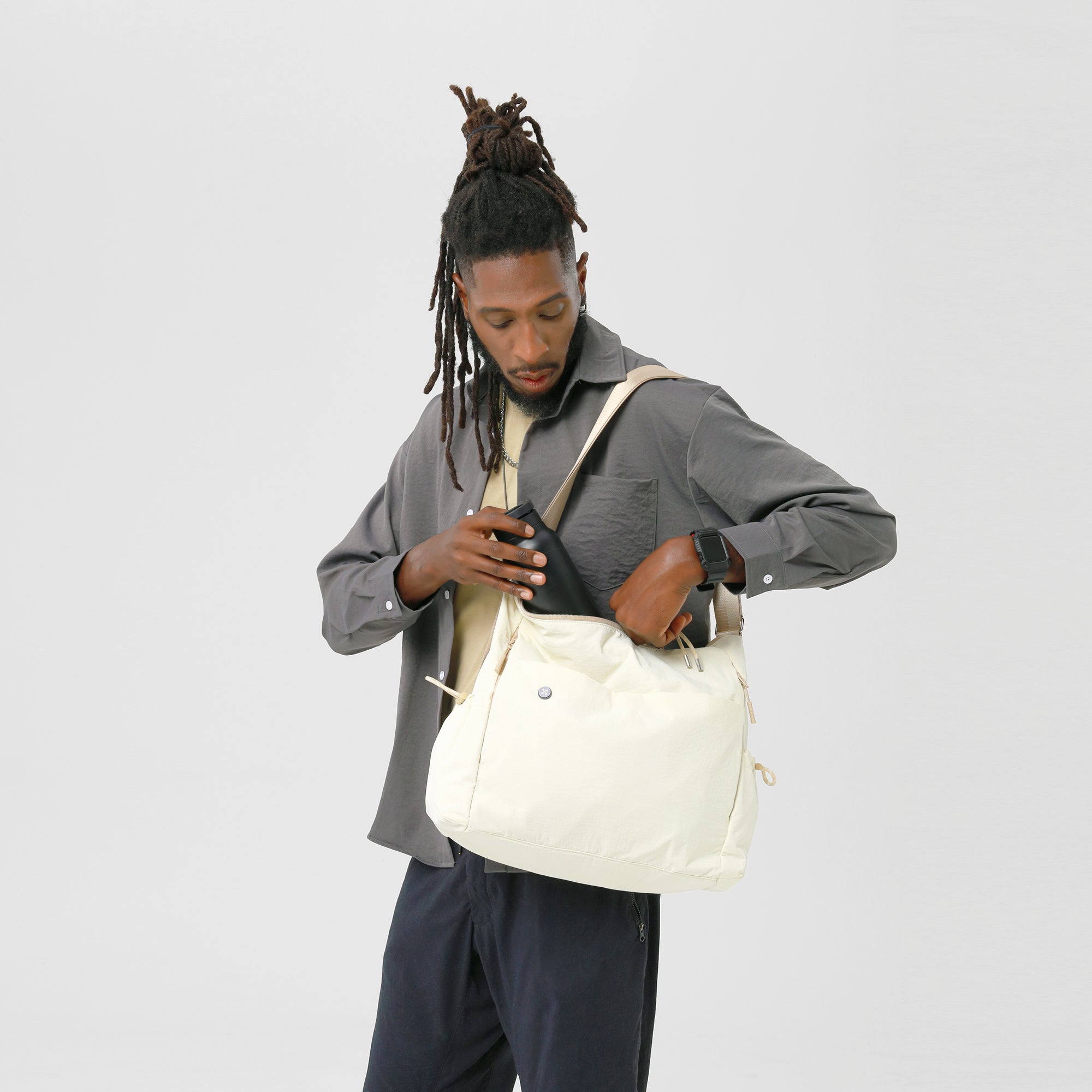 Man wearing gray shirt, using the Air Convert Tote made of organic fabric, showcasing its versatility and style.