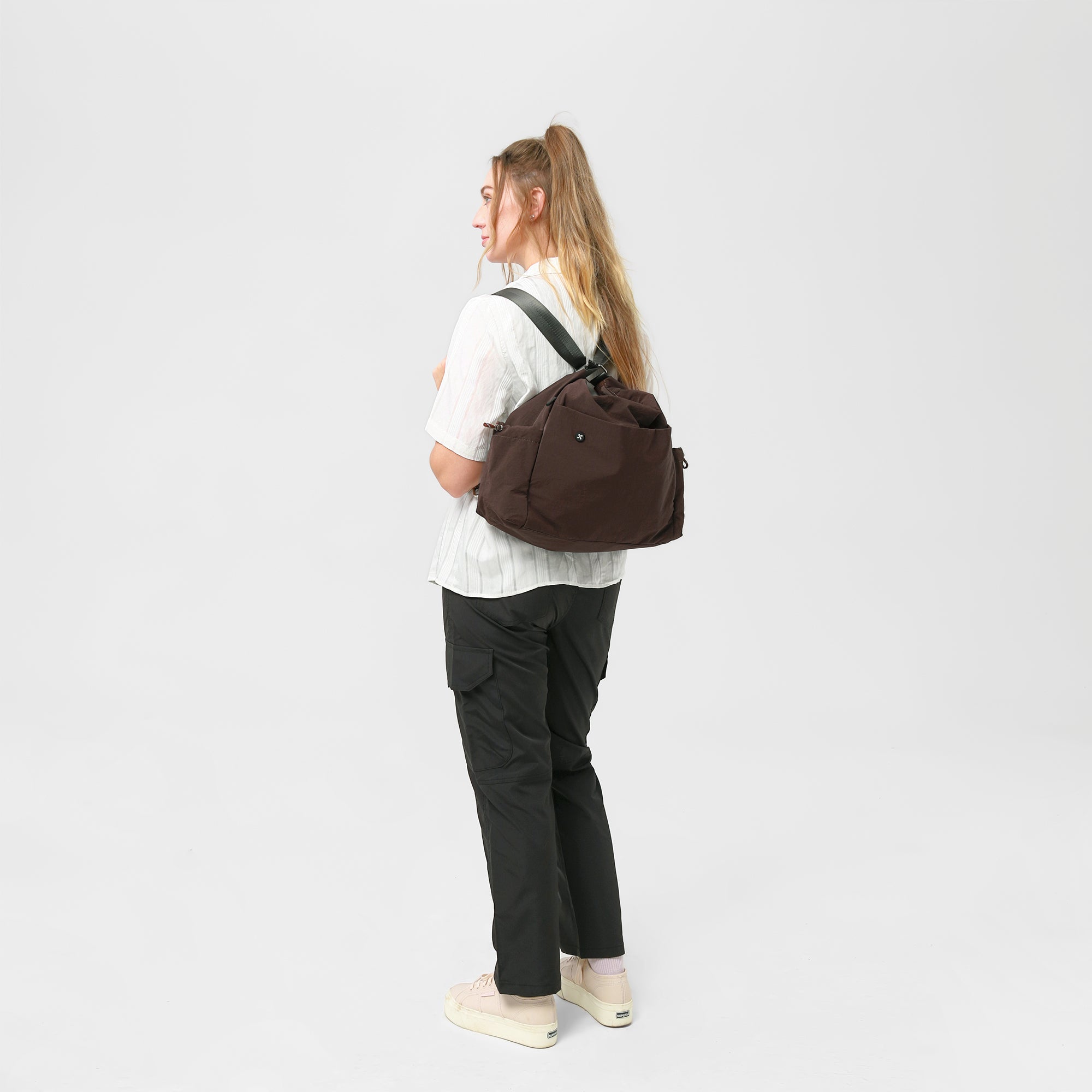 Woman wearing the Air Convert Tote, crafted from organic fabric for urban style and air comfort, showcasing its versatility.