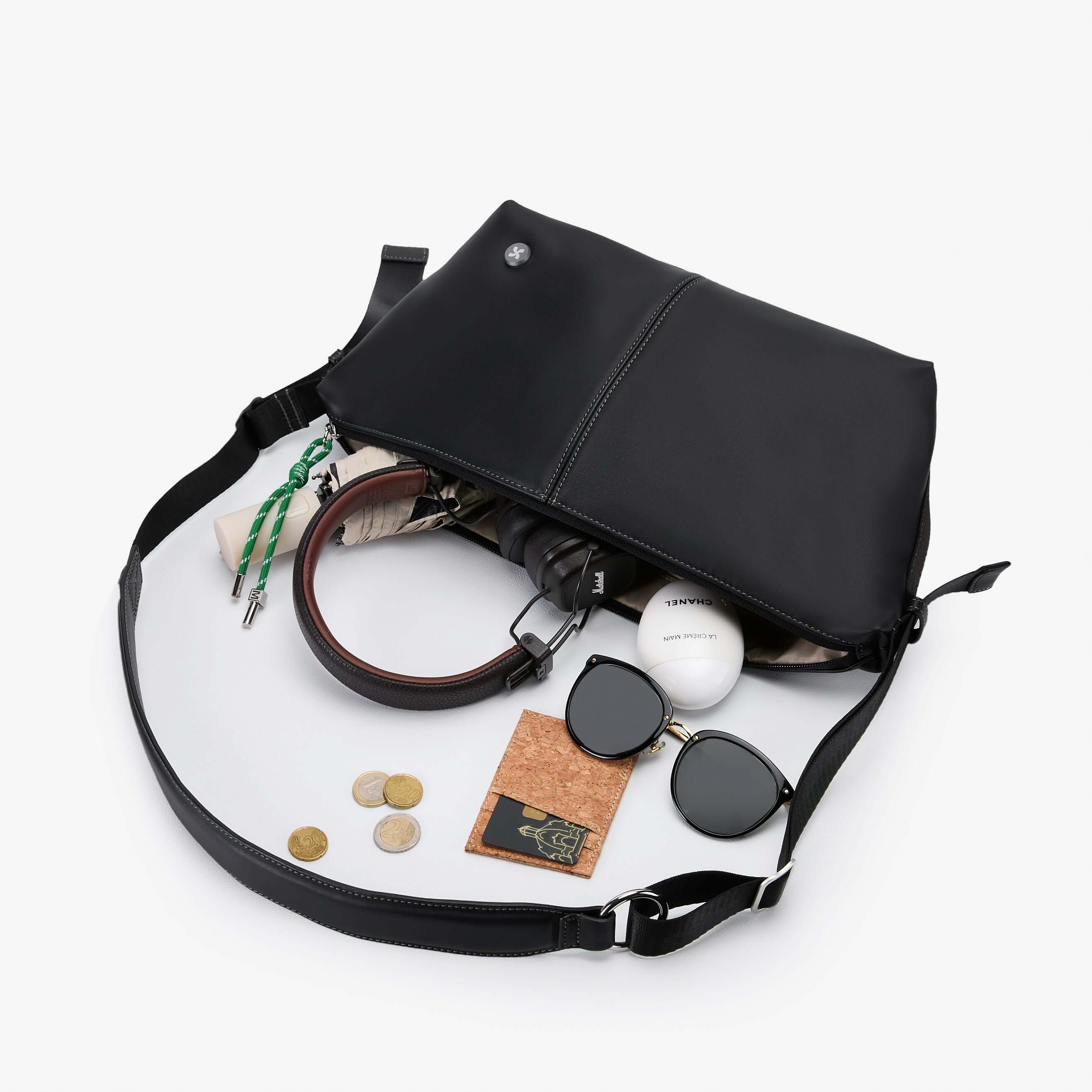 Urban Glide Crossbody bag with padded strap, featuring a stylish black design and items like sunglasses and coins inside.