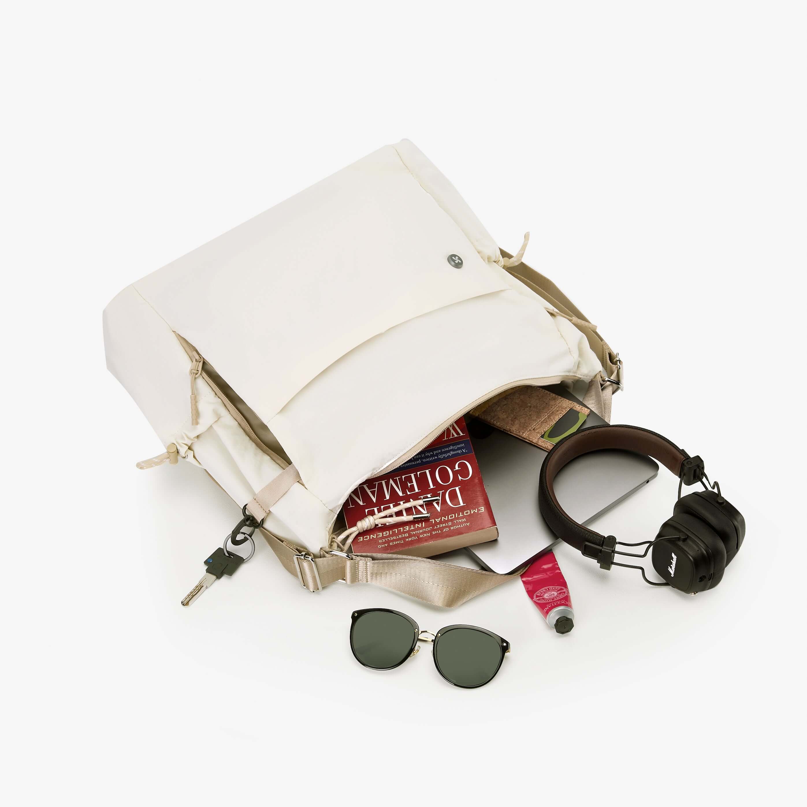 Air Convert Tote in organic fabric with books, sunglasses, and headphones, designed for urban convenience and style.