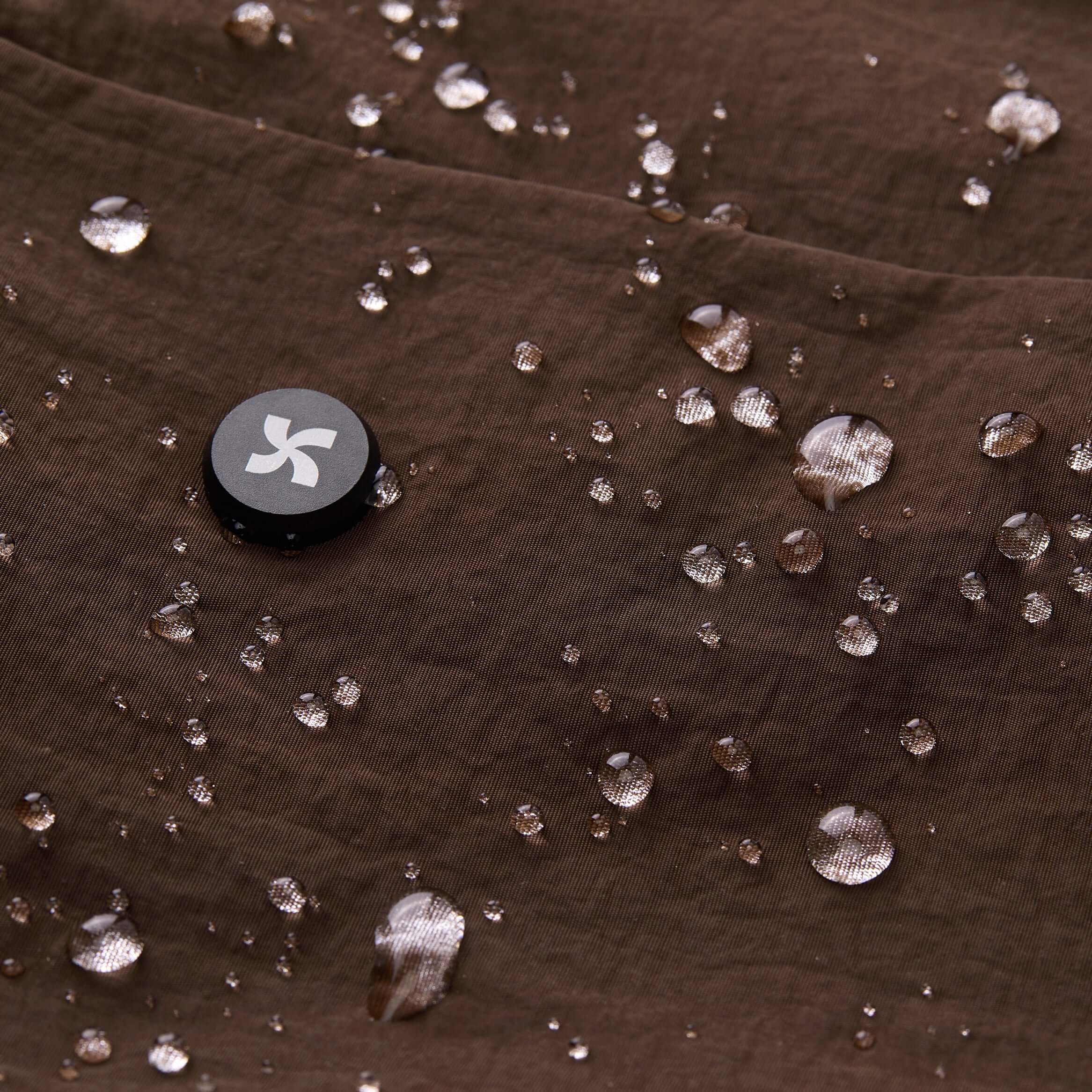 Close-up of water droplets on the brown organic fabric of the Air Convert Tote featuring the Mopak logo.