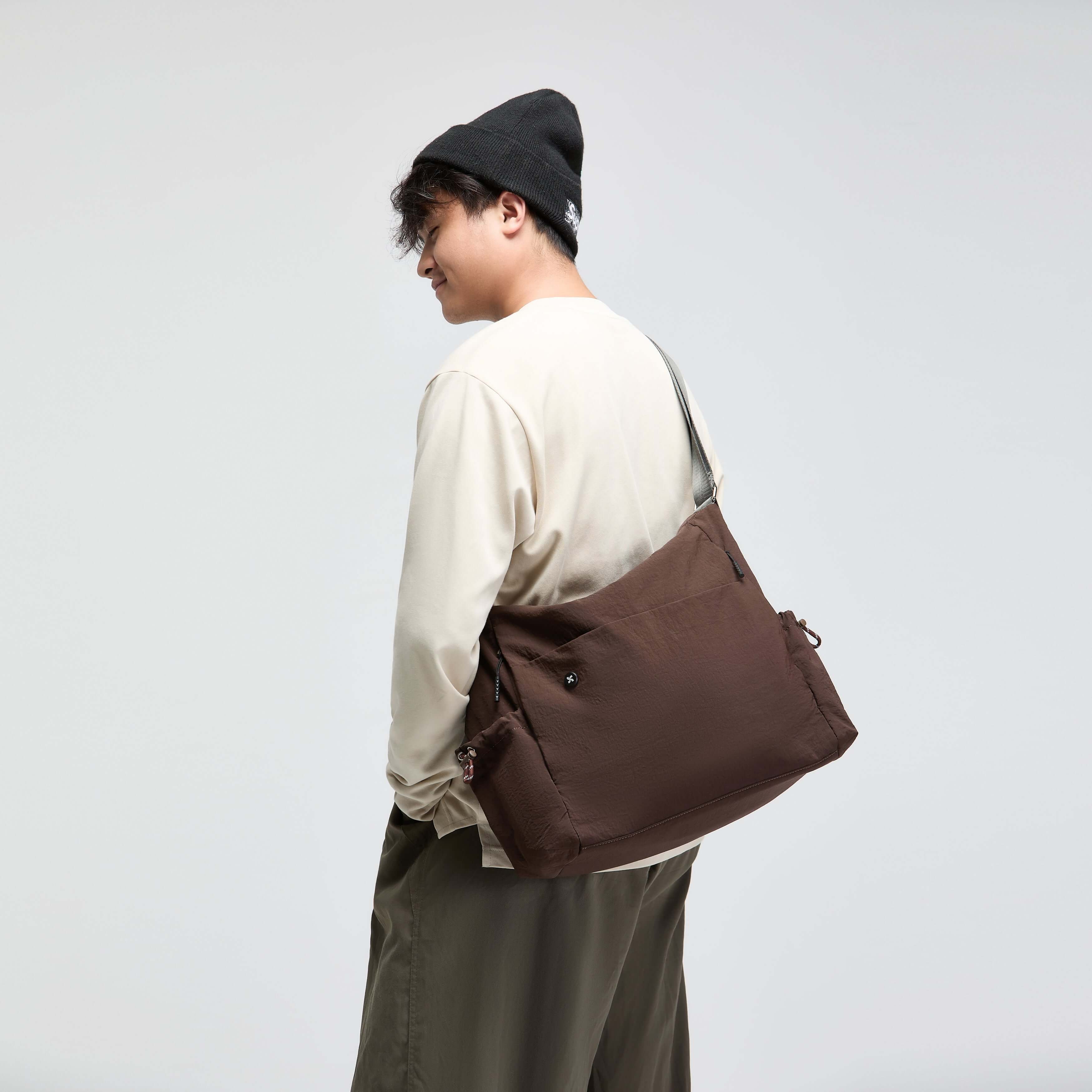 Model wearing the Air Convert Tote, an organic fabric bag, showcasing its versatile design and urban style.