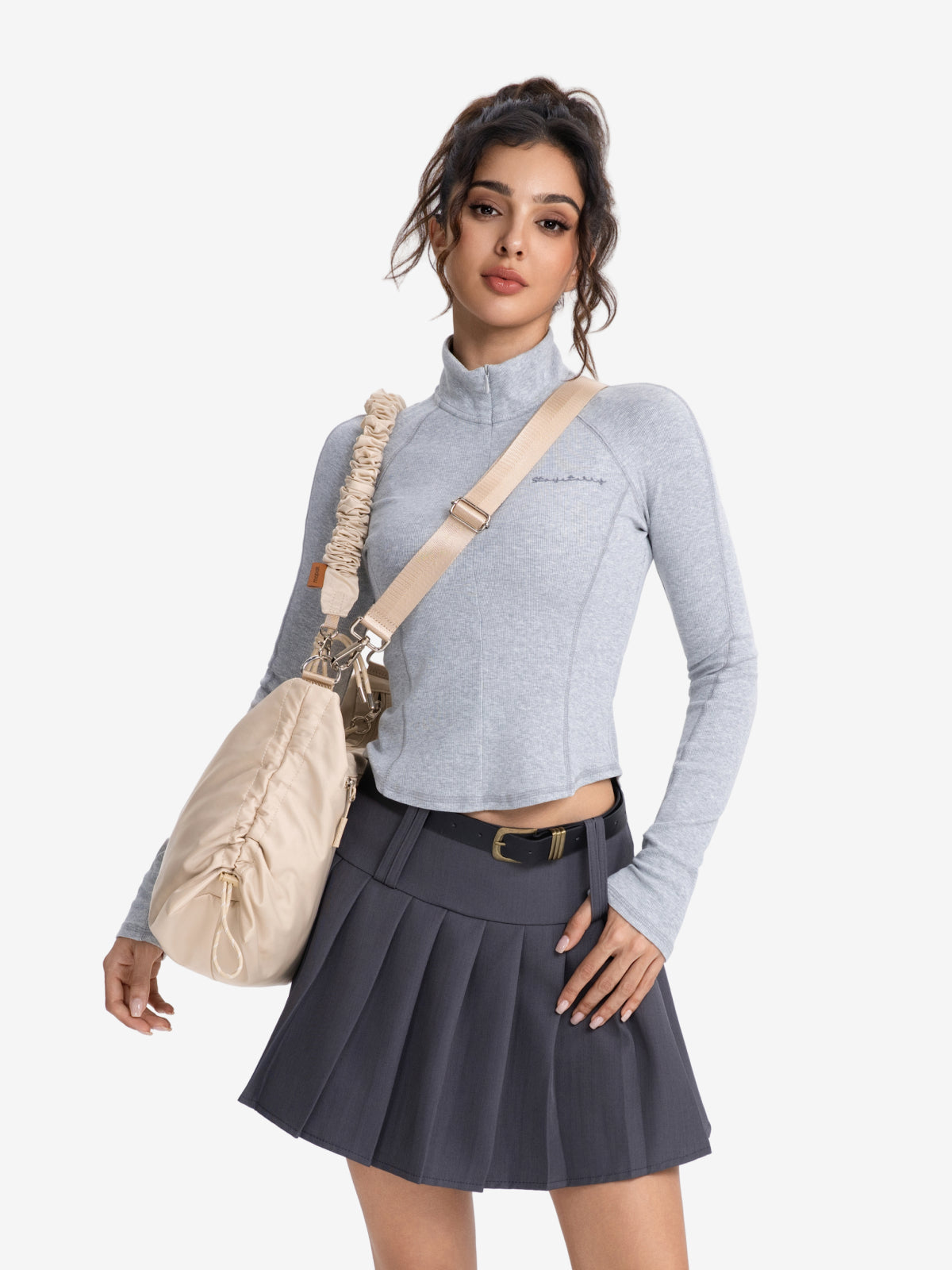 Woman wearing a gray top and a pleated skirt, carrying a Lumen Luna set bag for a stylish look.