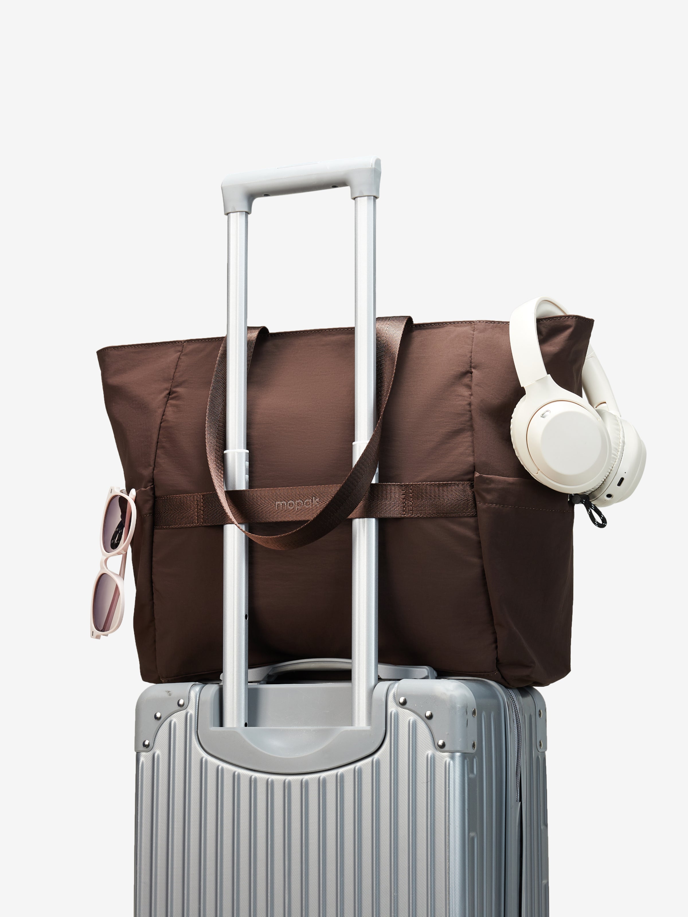 Air Daily Tote on a rolling suitcase with headphones and sunglasses.