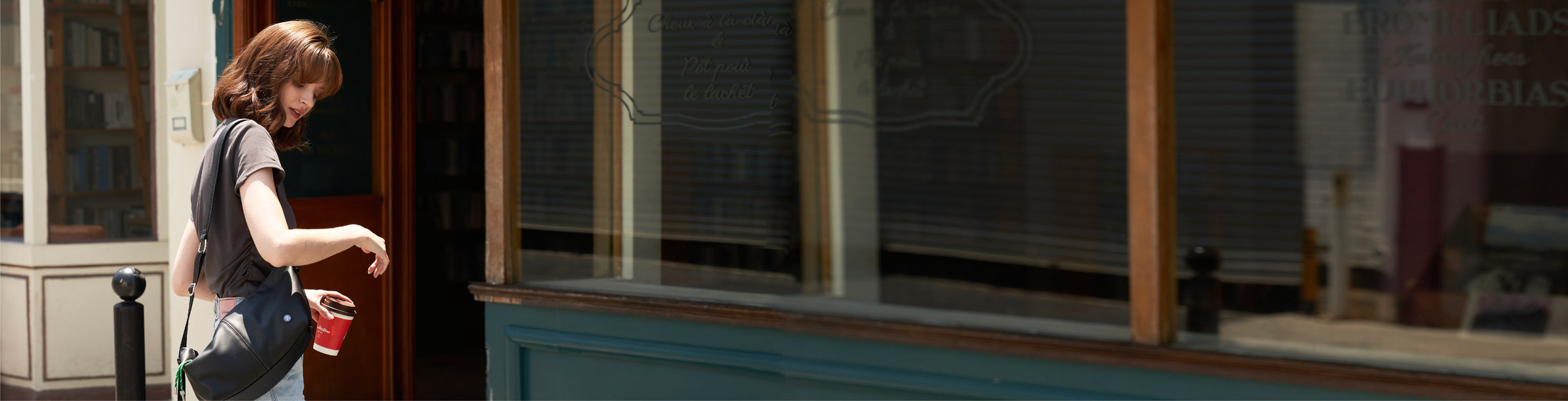 Woman walking past a store window with reflections - mopak city walk with sling bag