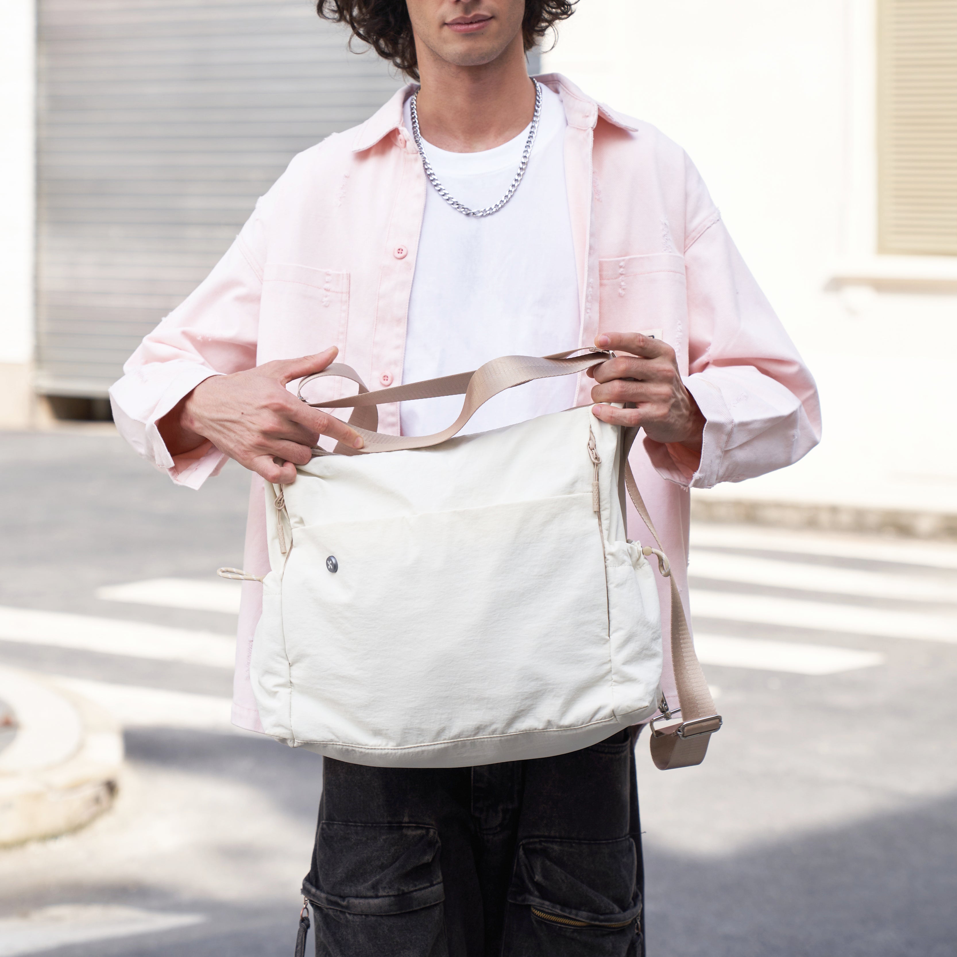 a man holding a white mopak tote bag outdoors on a sunny day