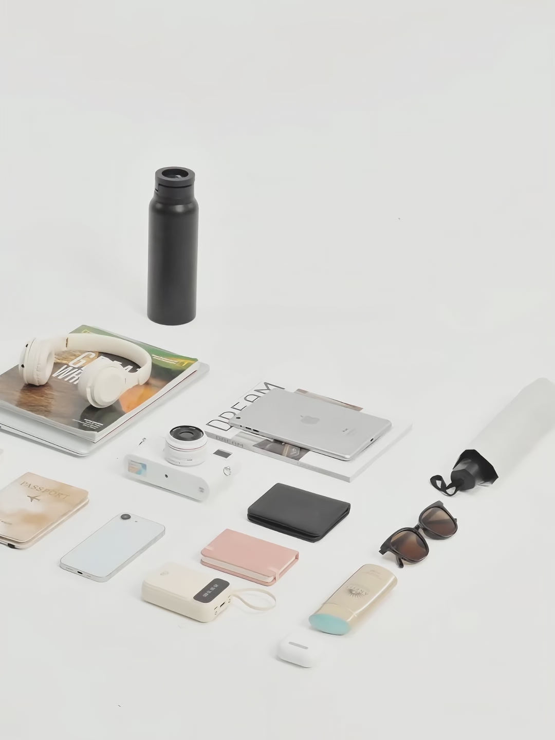A stylish flat lay of urban essentials including headphones, a camera, a laptop, and a water bottle, showcasing modern exploration.